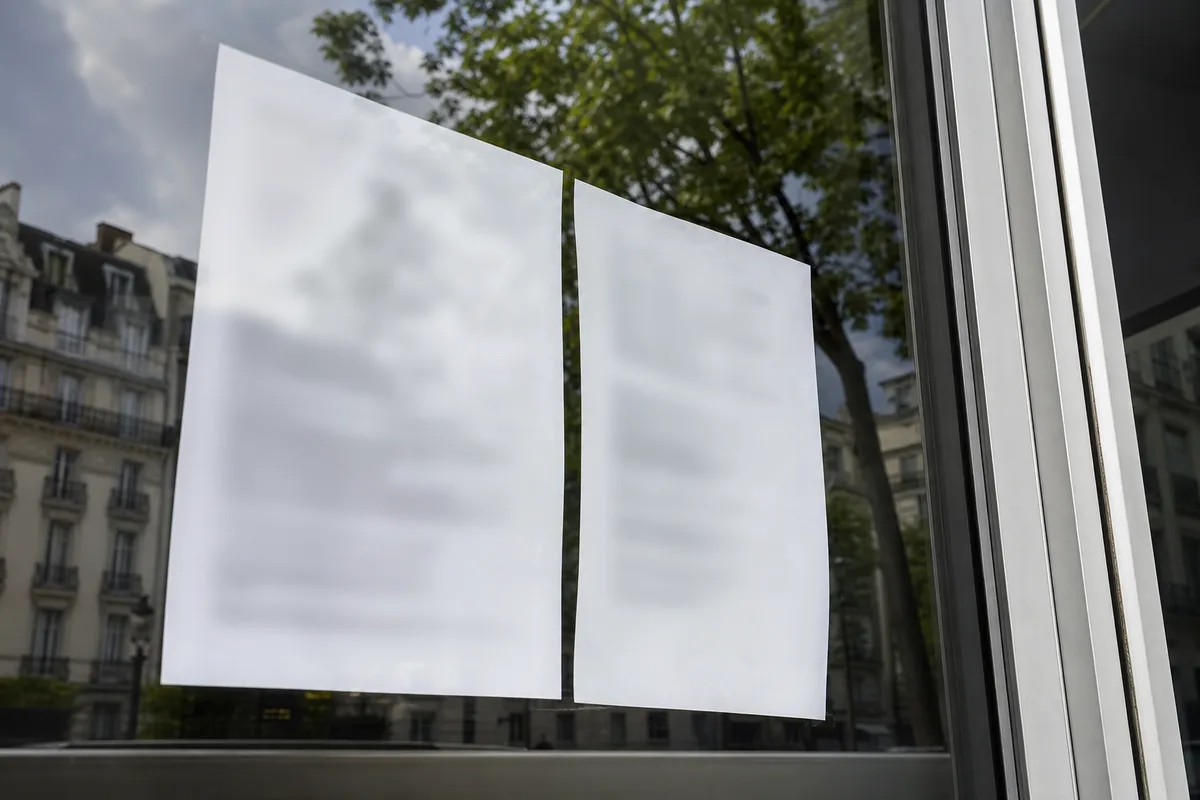 Deux affiches de taux de réussite collées sur la vitre d’un local d’auto-école, vue de trois quarts