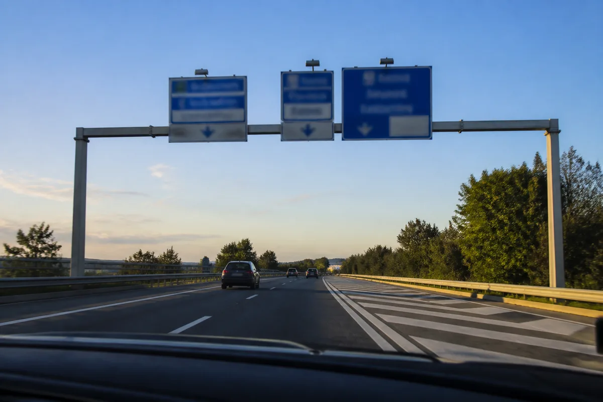 Panneaux de direction au-dessus d’une route à deux voies en approche de carrefour